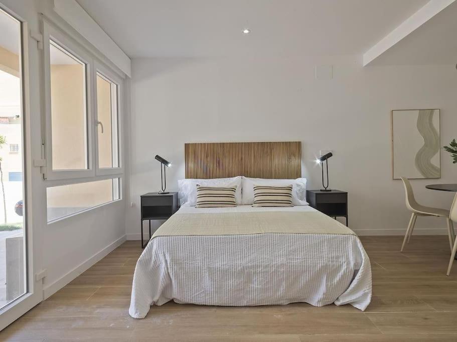 a white bedroom with a large bed with two lamps at Estudio Temporal a 2' de la playa de Sagunto A2 in Puerto de Sagunto