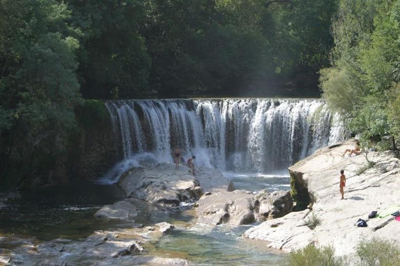 une cascade avec des personnes debout devant elle dans l'établissement Appartement , terrasse tropezienne proche Cascade de la Vis, à Saint-Laurent-le-Minier