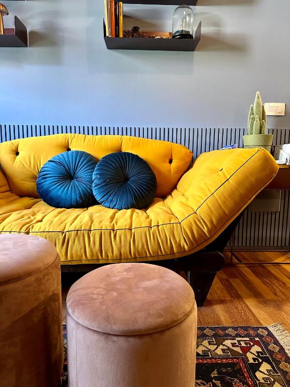un sofá amarillo con almohadas azules en una habitación en LR Deluxe Apartments - Maison Zeno, en Milán