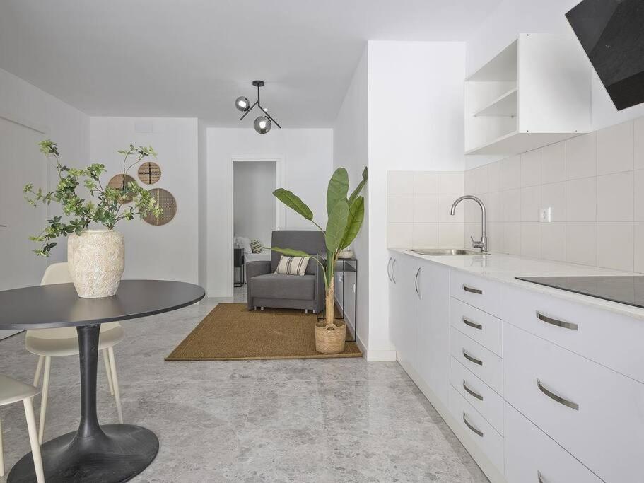 a white kitchen with a table and a chair at Oasis Junto al Mar a 2 minutos de playa Sagunto A6 in Puerto de Sagunto