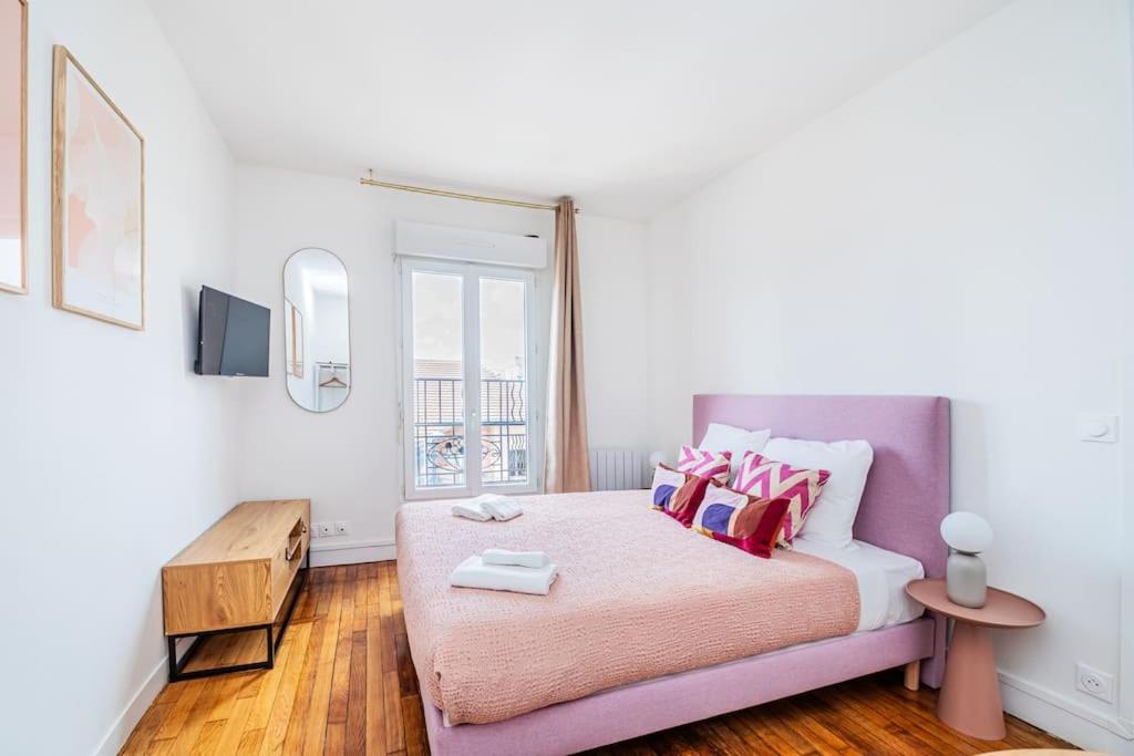 - une chambre avec un lit avec des draps roses et une fenêtre dans l'établissement Charmant studio en banlieue parisienne - Montreuil, à Montreuil
