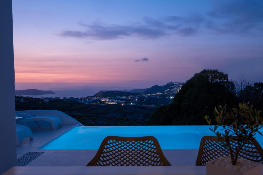 a pool with a view of the city at dusk at White Orchid Villa in Pyrgos