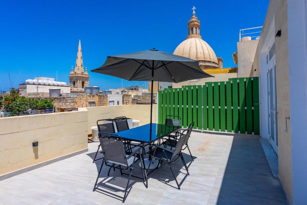 a table and chairs with an umbrella on a balcony at Penthouse Cathedral and Seaview Terrace V2 in Valletta