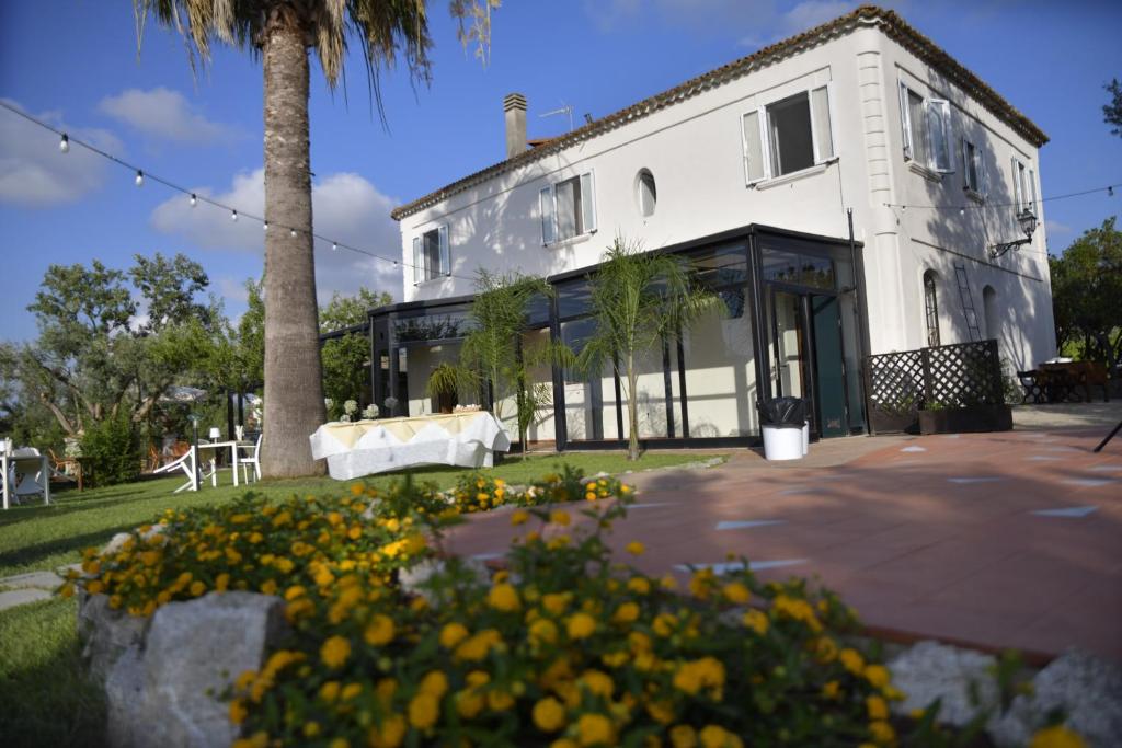 a white house with a palm tree and yellow flowers at Torre Galli-Dimora di Campagna in Gasponi
