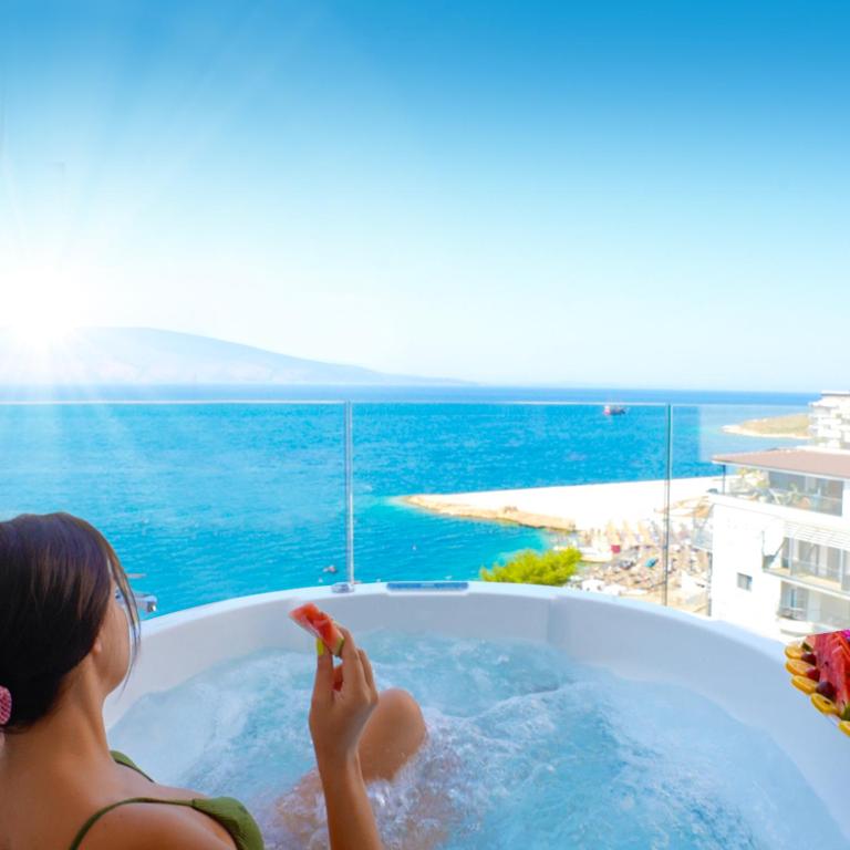 a woman in a jacuzzi tub with the ocean at DREAM HOTEL SARANDA in Sarandë