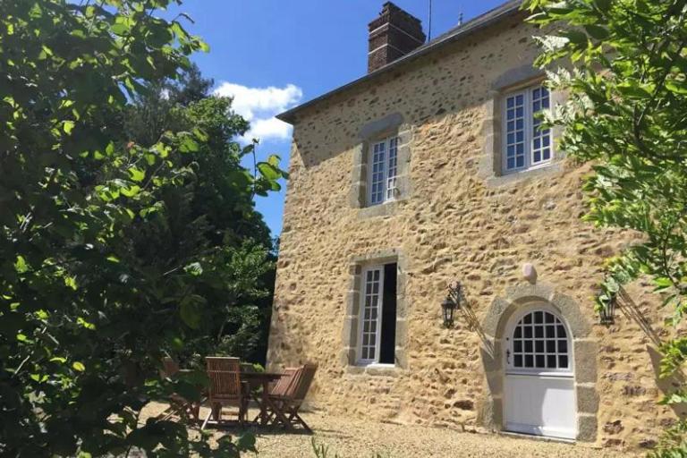 un bâtiment en pierre avec deux bancs devant lui dans l'établissement Gîtes du domaine des Vaulx, à La Baconnière