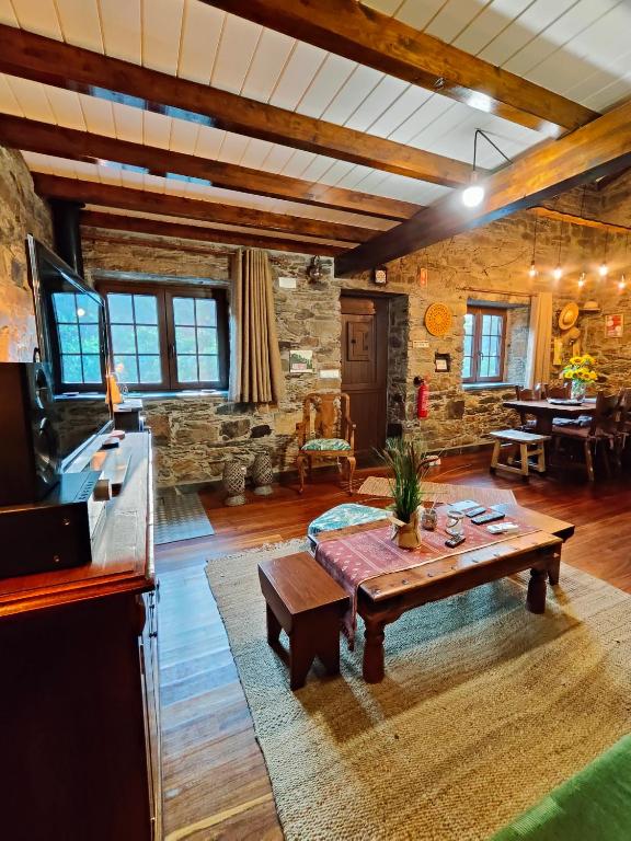 a living room with a table and a stone wall at Azoka by the River- Proença-a-Nova in Maljoga de Proença