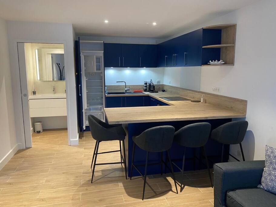 una cucina con armadi blu e un bar con sgabelli di Appartement T2 Pyla-sur-mer a La Teste-de-Buch