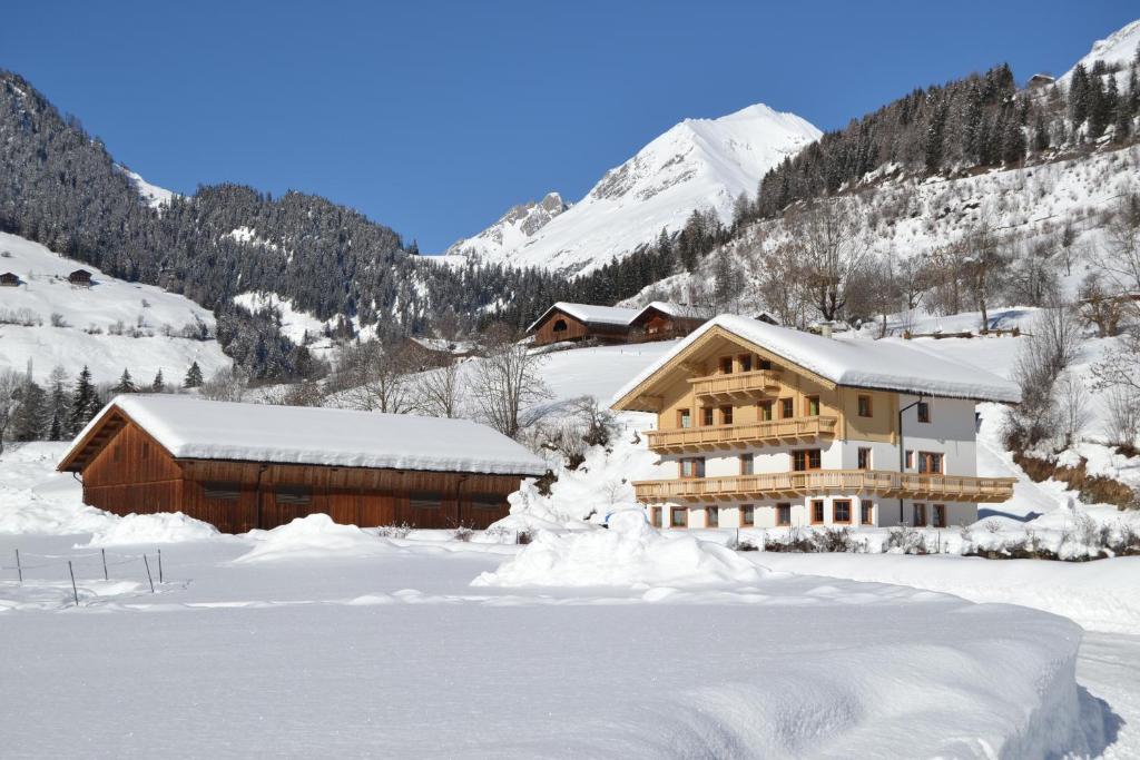 a large building in the snow with mountains in the background at Apartment Santnerhof in Virgen