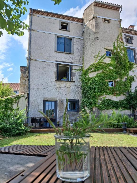 un vase assis sur une table en bois devant un bâtiment dans l'établissement Côté Tour, à Orcet