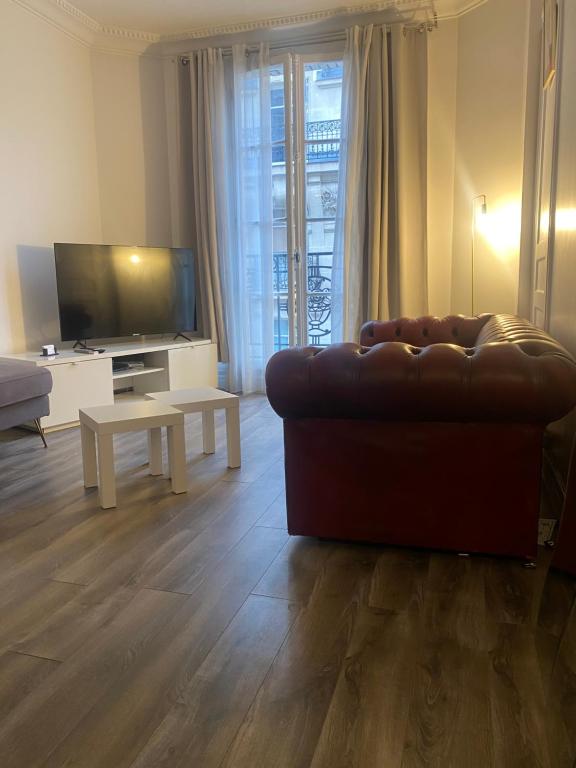 un salon avec un canapé en cuir et une télévision dans l'établissement AG Immobilier 75, à Paris
