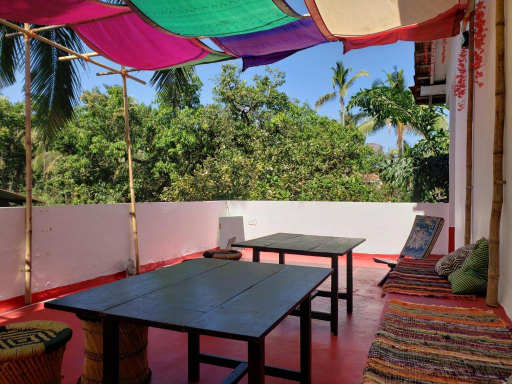 two tables on a porch with an umbrella at Laxmi Happy Home in Querim Goa in Querim