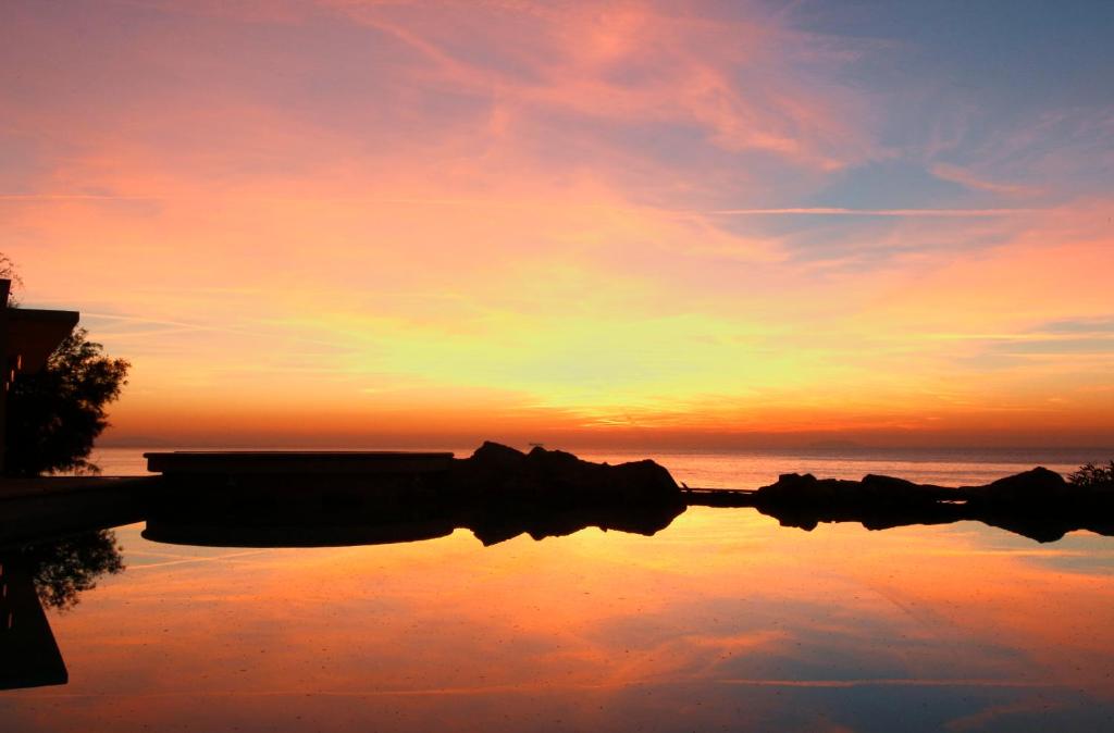 a reflection of a sunset in a body of water at Hotel Villa Margherita in Quercianella