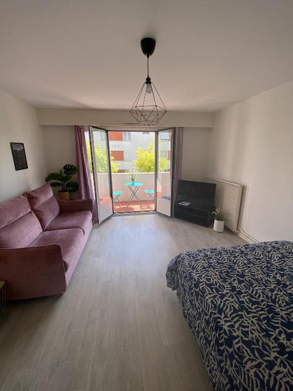 een woonkamer met een bed en een bank bij Grand Studio avec loggia in Thorigny-sur-Marne