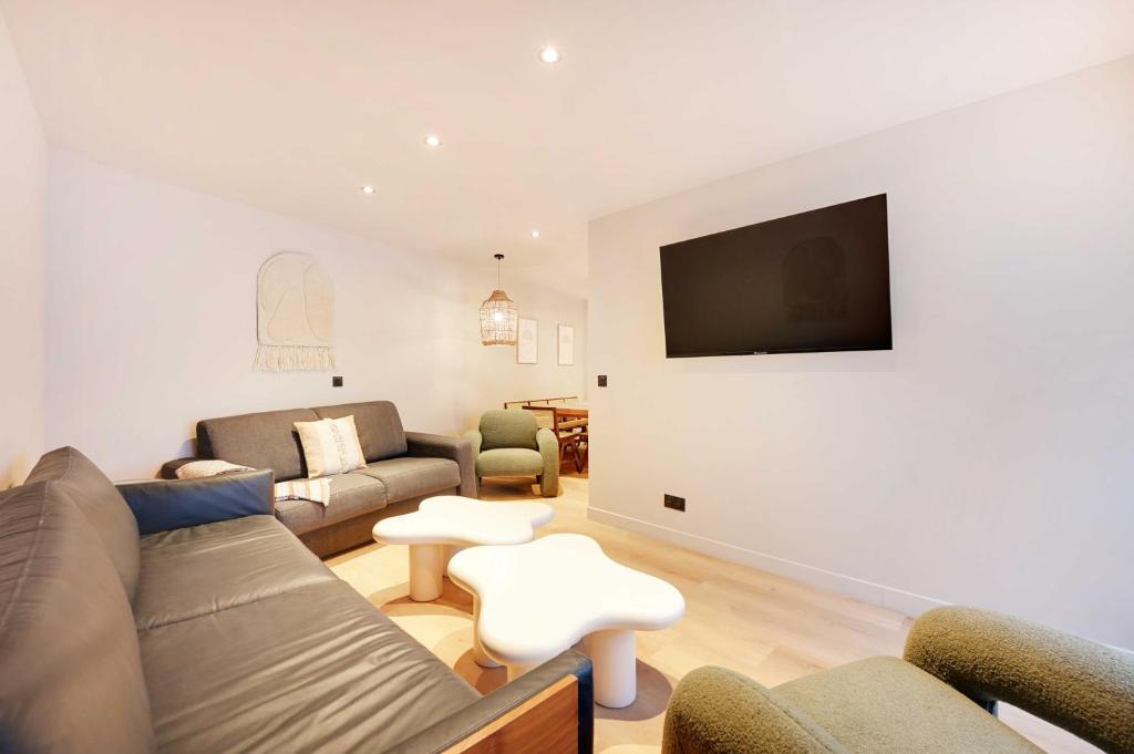 un salon avec un canapé et une télévision sur un mur dans l'établissement Magnificent Apt - 3BD-10P - Buttes aux Cailles, à Paris