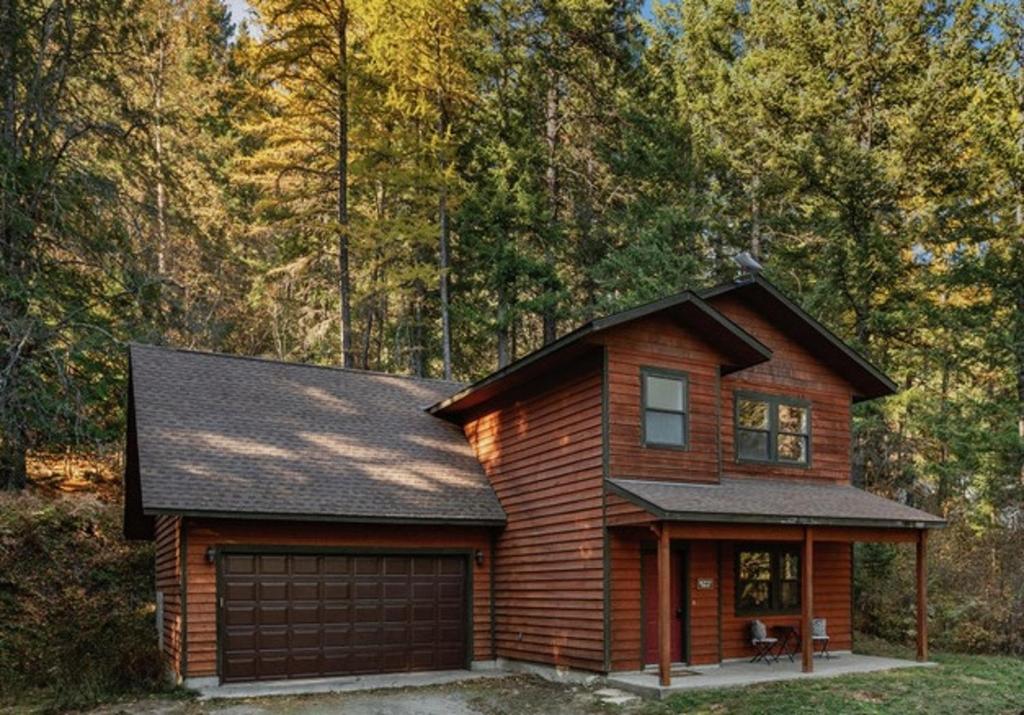 a log house with a garage in the woods at Family Home - Sandpointschweitzer in Sandpoint