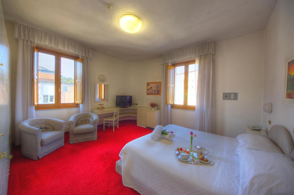 a bedroom with a white bed and a red carpet at Grand Hotel Milano in Chianciano Terme