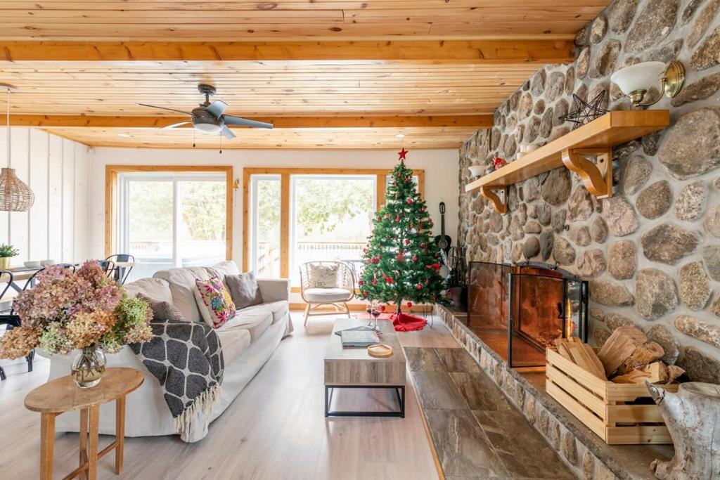 sala de estar con chimenea de piedra y árbol de Navidad en Casa Olej Unforgettable getaway in Tremblant & SPA, en Saint-Rémi-dʼAmherst