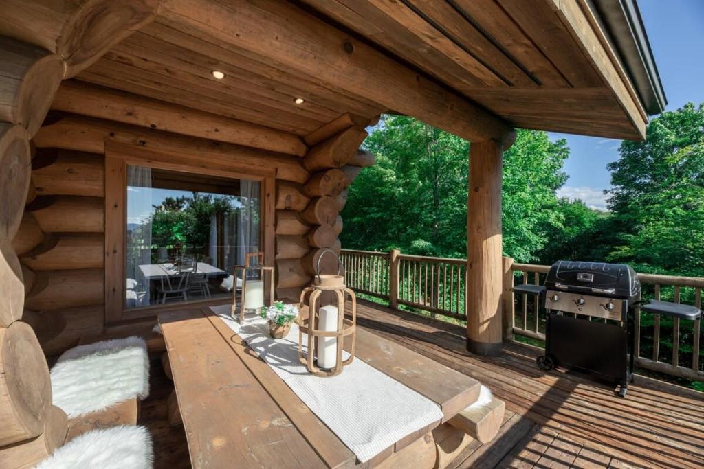 a log cabin deck with a grill and a table at Chalet Chic Rustique & SPA - Tremblant in Lac-Superieur