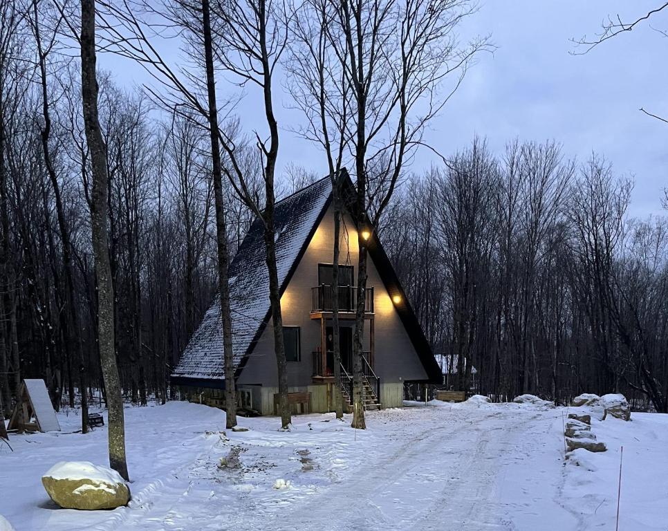 ein kleines Haus im Schnee mit Lichtern drauf in der Unterkunft Kartalla - the A frame experience in Tremblant in Saint-Rémi-dʼAmherst