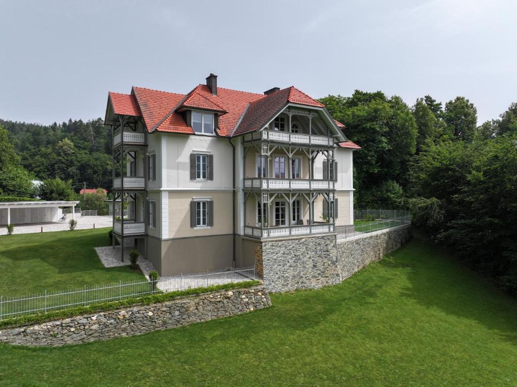 Villa Gloriette - BoutiqueAppartements am Wörthersee في بويرشاك آم فورثيرسي: اطلالة هوائية على منزل مع ساحة خضراء