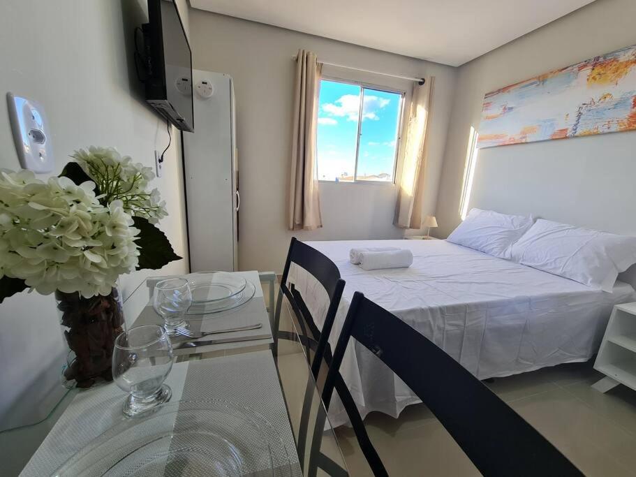 a small bedroom with a bed and a table with a glass table at Kitnet303 centro, c linda vista janela, tv smart in Montes Claros