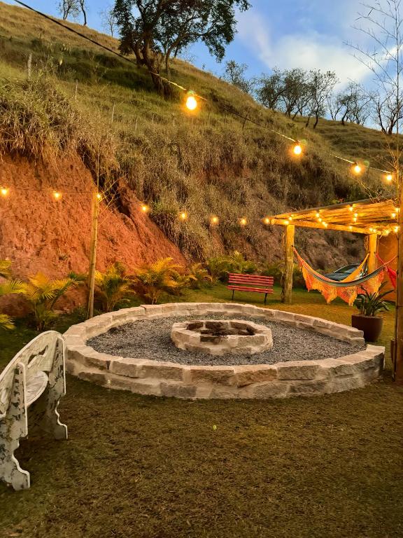 a fire pit in a yard with a bench and lights at Pousada Shangri-lá in Cunha