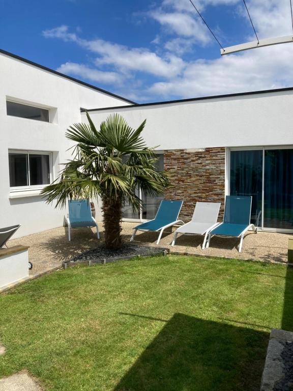 a group of chairs and a palm tree in a yard at maison avec piscine couverte in Louannec