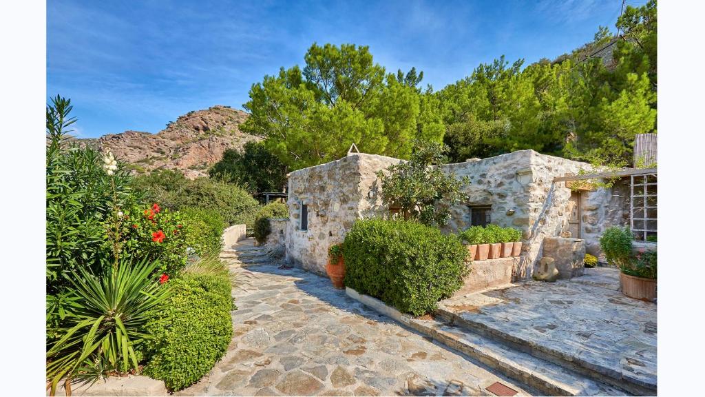 a stone house with plants and a pathway at White River Cottages - rustic minimalist holiday houses in Makry Gialos