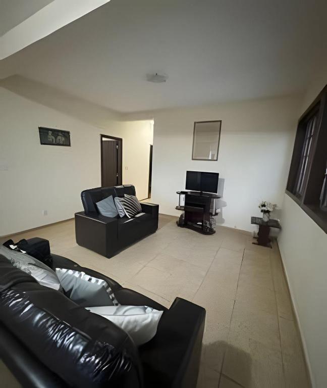 a living room with a leather couch and a piano at Sitio com Piscina AQUECIDa e 5 quartos c/ suíte! in Jaboticatubas