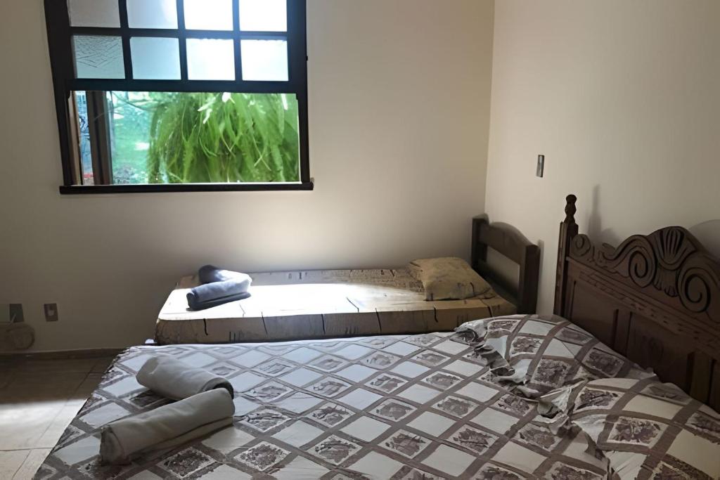 a bedroom with two beds and a window at Sitio com Piscina AQUECIDa e 5 quartos c/ suíte! in Jaboticatubas