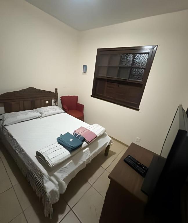 a bedroom with a bed with a chair and a window at Sitio com Piscina AQUECIDa e 5 quartos c/ suíte! in Jaboticatubas