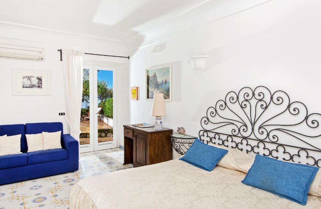 um quarto com uma cama e um sofá azul em Il Giardino dell'Arte em Anacapri