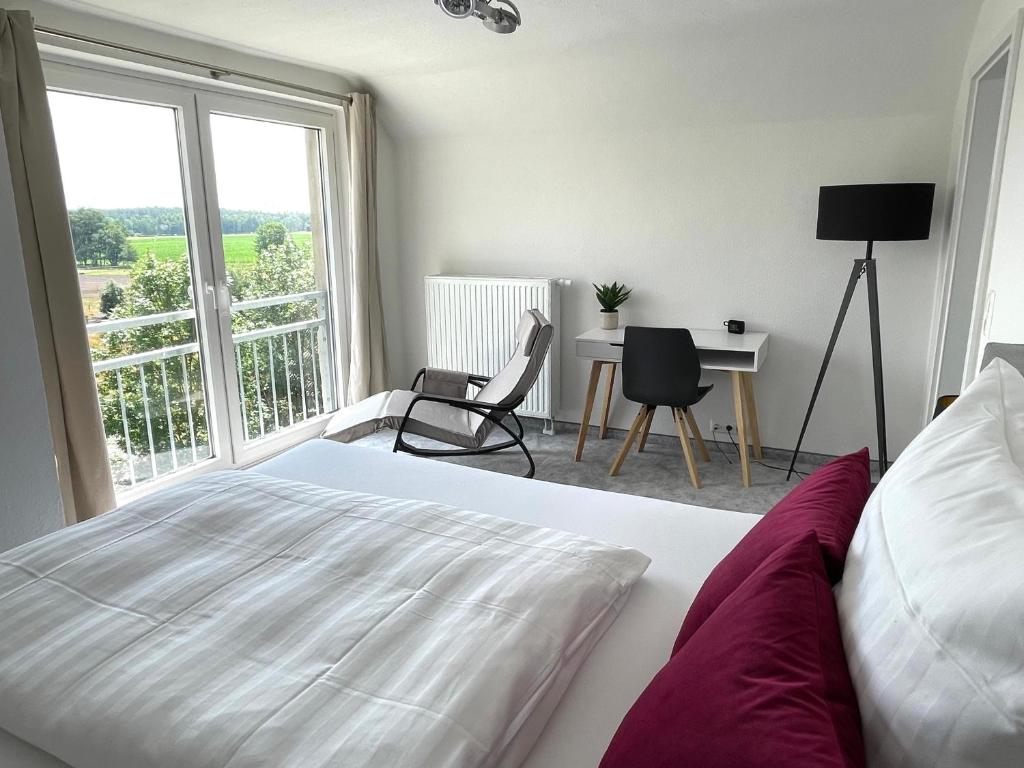 a bedroom with a bed and a desk and a window at Apartment mit Weitblick in Leppin