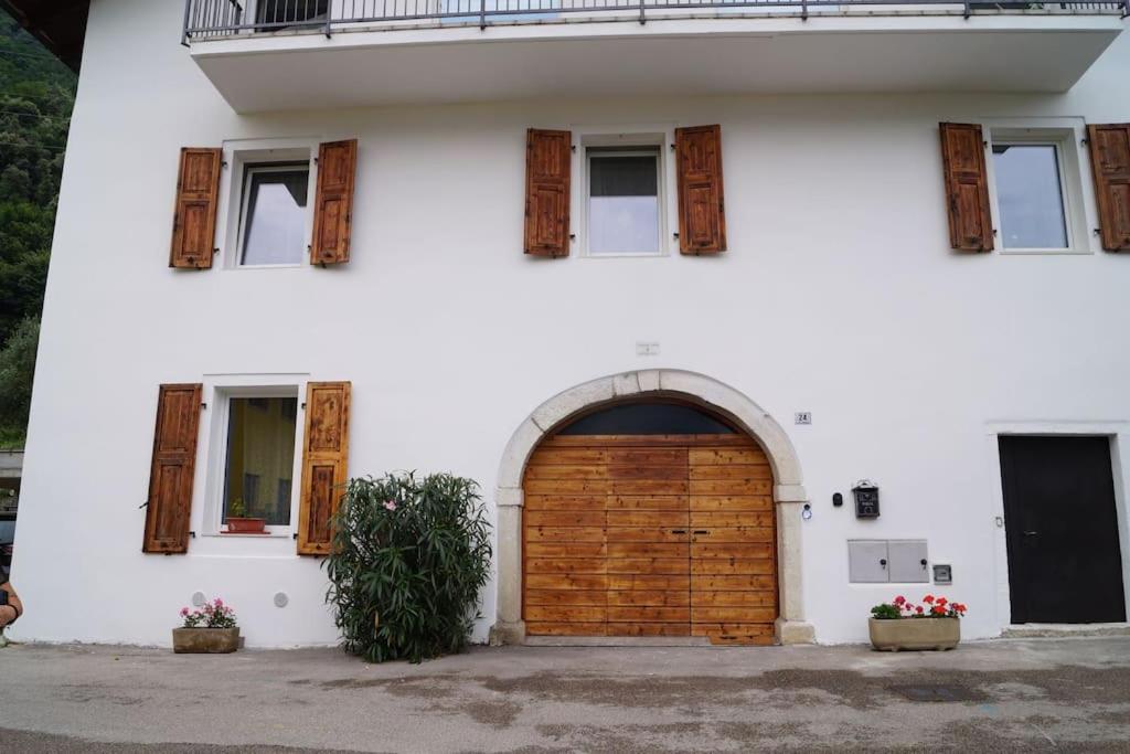 un grande edificio bianco con una porta in legno di villa Cretaccio Arco,bilocale in casa di campagna a 5 Min dal lago con deposito bici e attrezzatura ad Arco