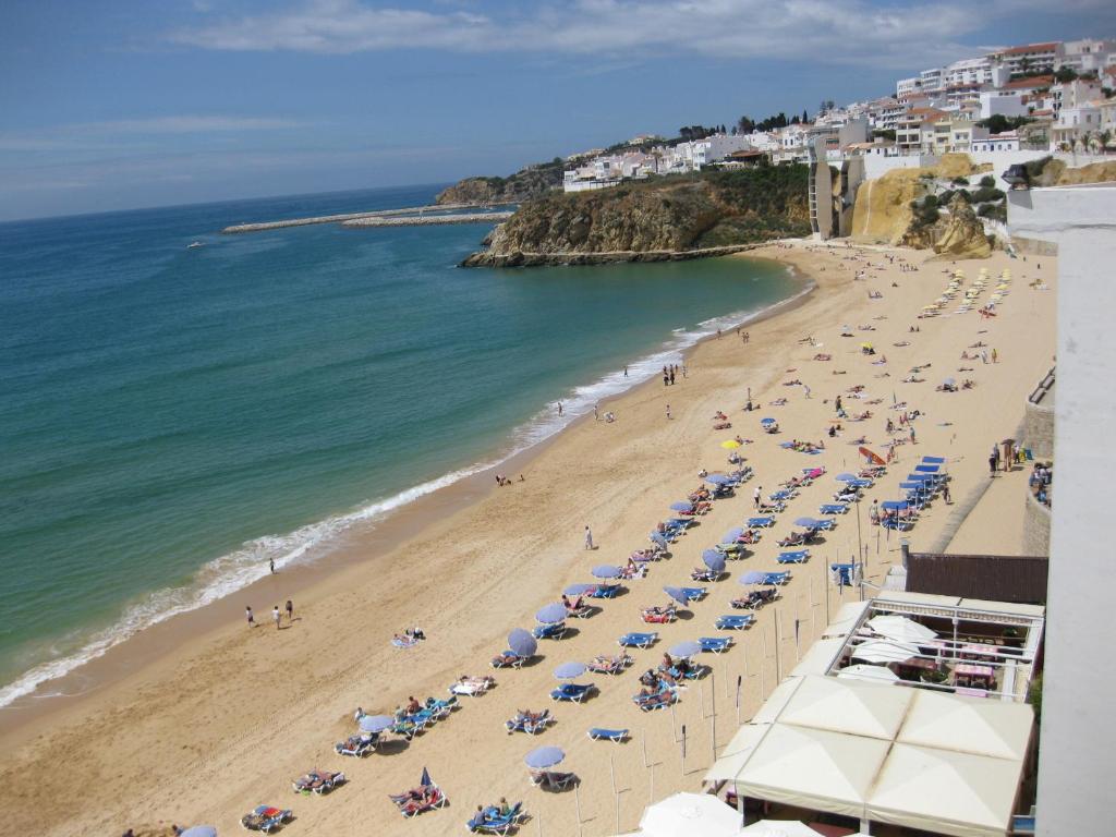 a beach with chairs and umbrellas and the ocean at Apartamento Silva in Albufeira