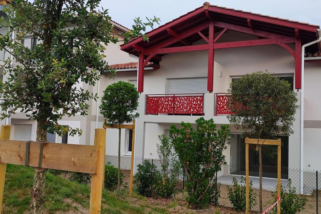 a house with a red balcony and a fence at location appartement in Soustons