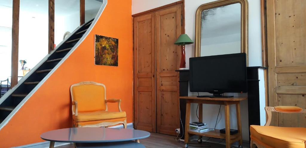- un salon avec un mur orange et une télévision dans l'établissement Lumineux Duplex à Wazemmes, à Lille