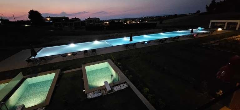 an overhead view of a swimming pool at night at Oikos Sani Suites in Sani Beach
