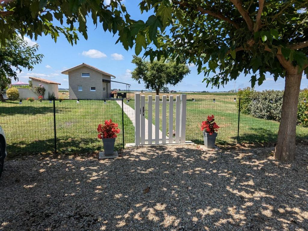 une clôture avec deux fleurs en pot devant un champ dans l'établissement Le Petit chalet - 2 étoiles au classement tourisme, à Birac-sur-Trec