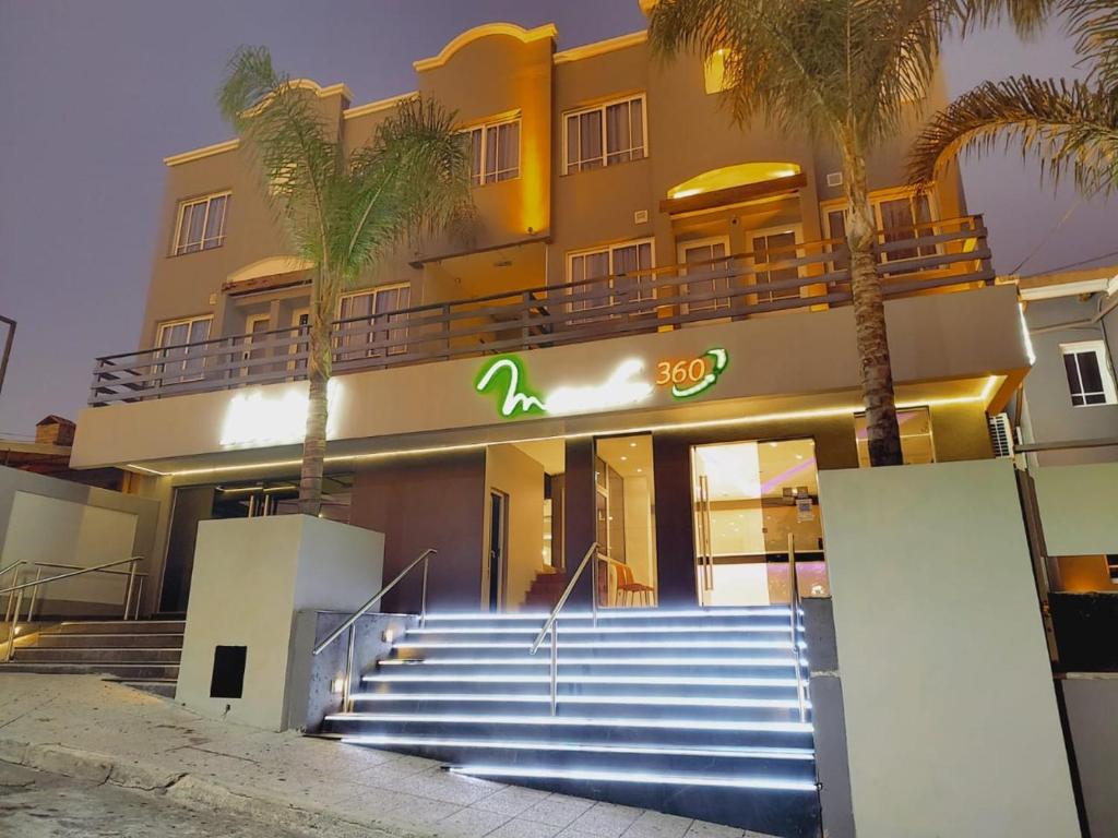 a building with stairs in front of a building with palm trees at Enjoy 360 in Villa Carlos Paz