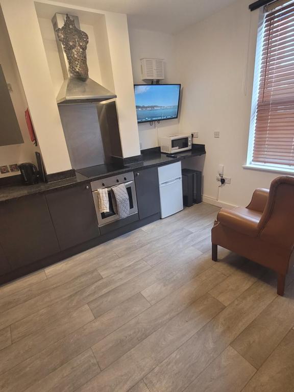 a living room with a kitchen and a couch and a television at Heart of City DE1 Studio Apartment in Derby