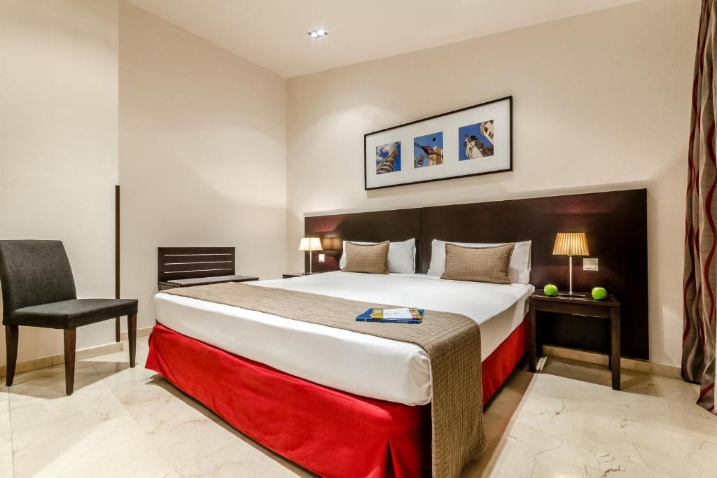 ein Hotelzimmer mit einem großen Bett und einem Stuhl in der Unterkunft Exe Suites 33 in Madrid