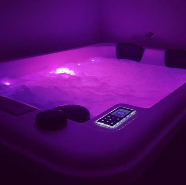 a hot tub with a cell phone in a purple room at My Suite in Bourgoin