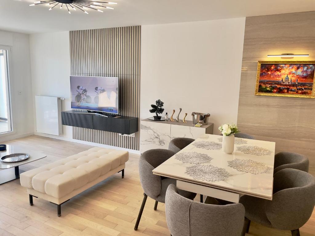 un salon avec une table, des chaises et une télévision dans l'établissement 4P luxe 200m de Paris vue Sacré Cœur, à Saint-Ouen