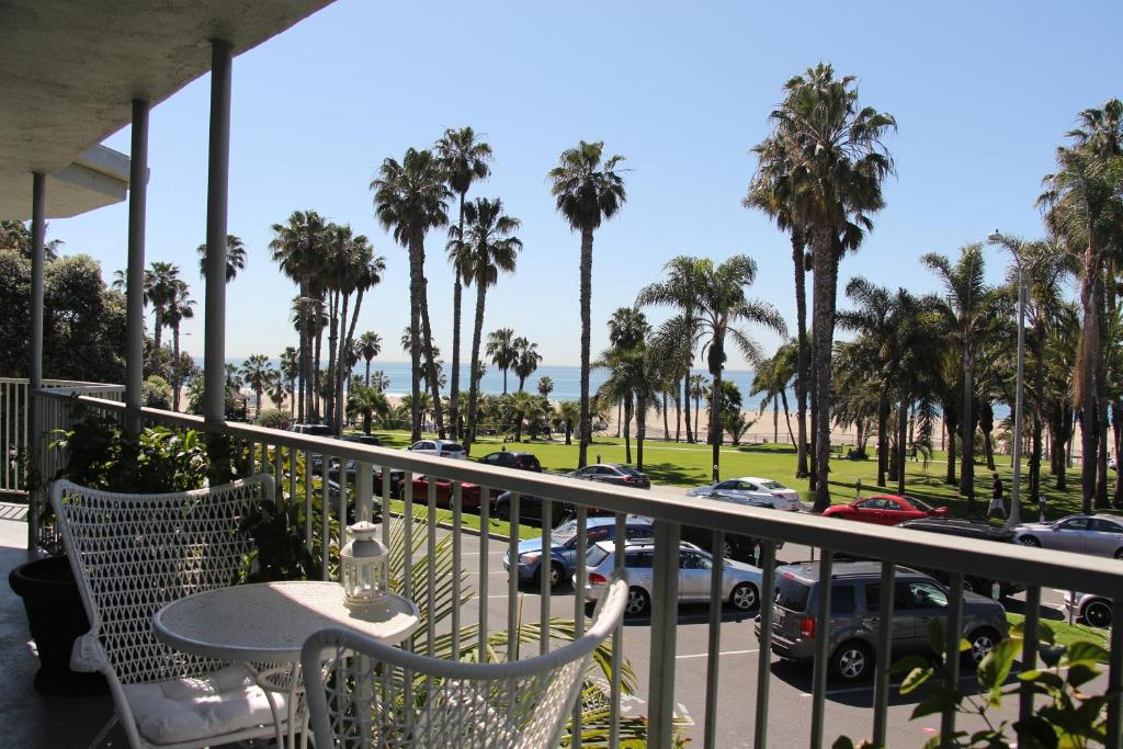 uma varanda com mesa, cadeiras e palmeiras em Bayside Hotel em Los Angeles