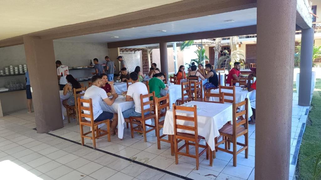 a group of people sitting at tables in a restaurant at Hotel Pousada Cumbuco Gold in Cumbuco