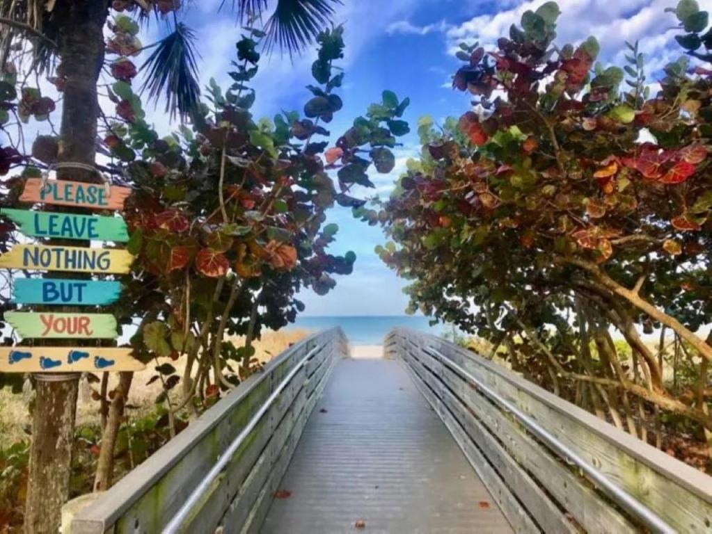 a boardwalk to the beach with signs and flowers at Seaside Retreat Cottages #4 in Clearwater Beach
