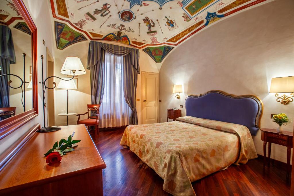 - une chambre d'hôtel avec un lit et un plafond orné de peintures dans l'établissement Hotel Fortuna, à Pérouse