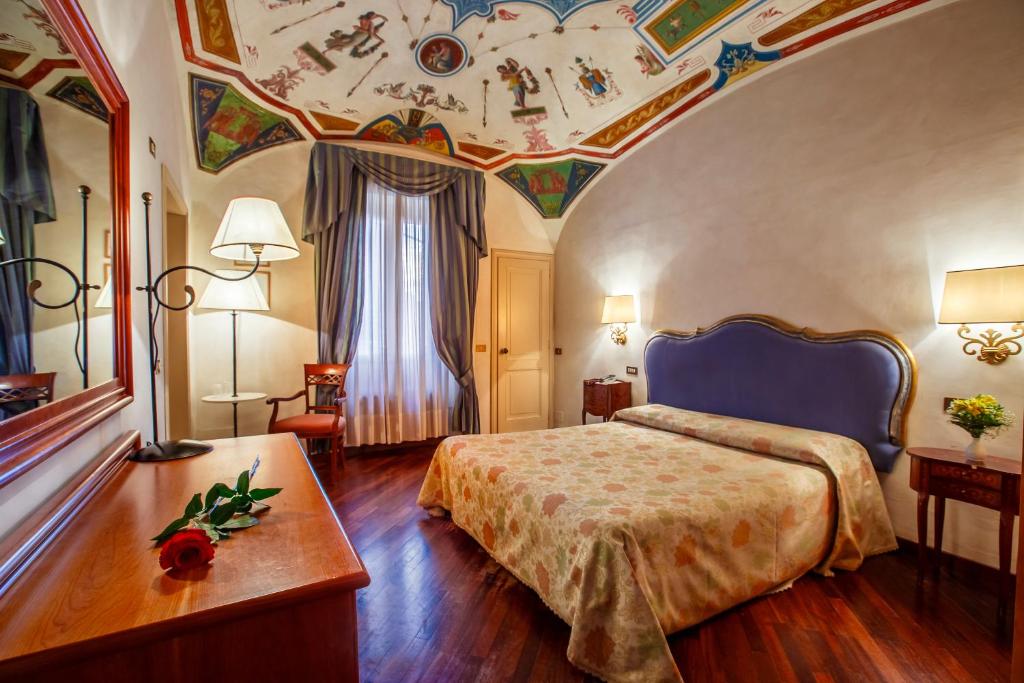 a hotel room with a bed and a ceiling with paintings at Hotel Fortuna in Perugia
